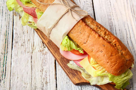 Board with tasty ciabatta sandwich on light wooden background, closeupの写真素材