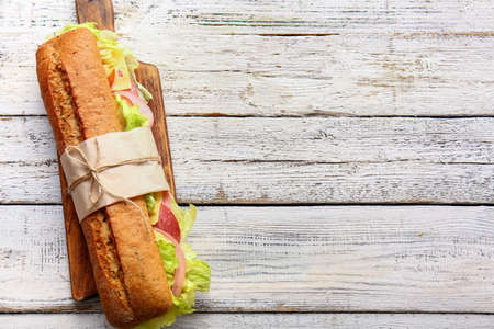 Board with tasty ciabatta sandwich on light wooden backgroundの写真素材