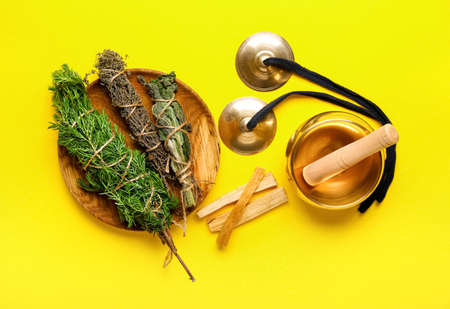 Tibetan singing bowl, karatalas, Palo Santo and herbs for aura cleansing on color backgroundの写真素材