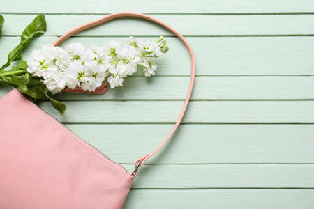 Stylish female handbag and beautiful flowers on color wooden backgroundの写真素材