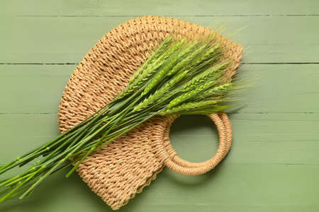Green wheat spikelets and bag on wooden background