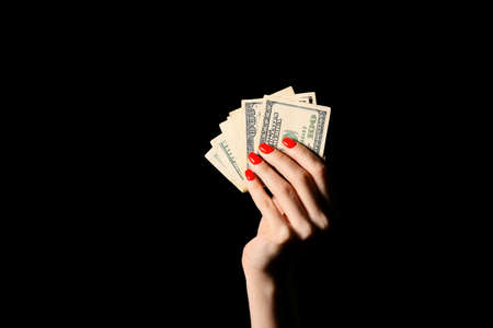 Woman with beautiful manicure holding money on dark backgroundの写真素材