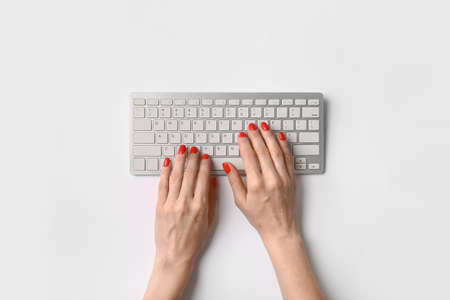 Woman with beautiful manicure and computer keyboard on white backgroundの写真素材