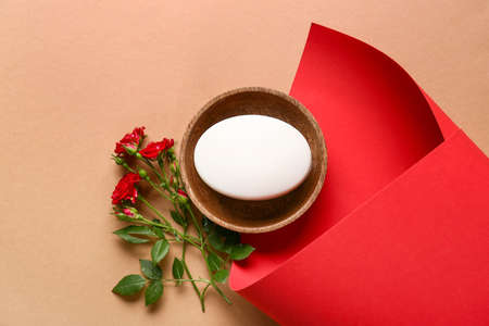 Composition with soap bar, flowers and sheet of paper on color background