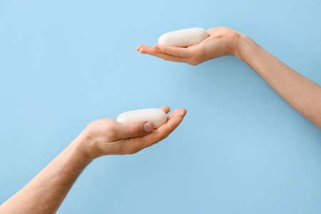 Male and female hands with soap bars on color backgroundの写真素材