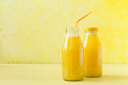 Bottles of tasty pineapple smoothie on color backgroundの写真素材
