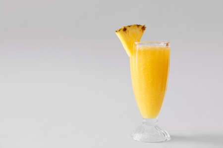Glass of tasty pineapple smoothie on gray background