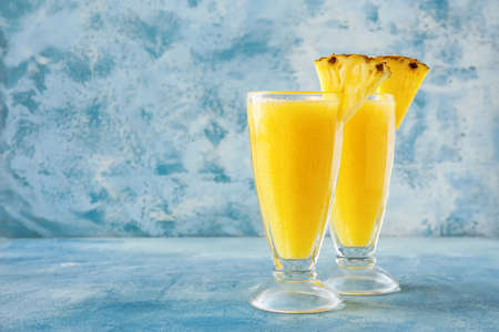 Glasses of tasty pineapple smoothie on color background