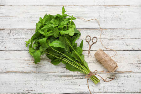 Bunch of mint, rope and scissors on wooden background