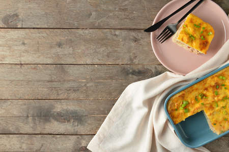 Plate with piece of mashed potato casserole on wooden backgroundの写真素材