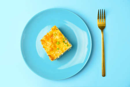 Plate with piece of mashed potato casserole on color background