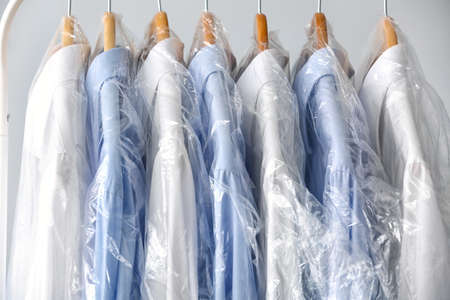 Rack with clean shirts in plastic bags on gray backgroundの写真素材