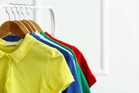 Rack with clean t-shirts near light wall