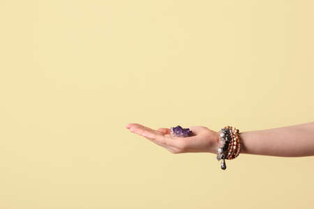 Female hand with beautiful amethyst on color backgroundの写真素材