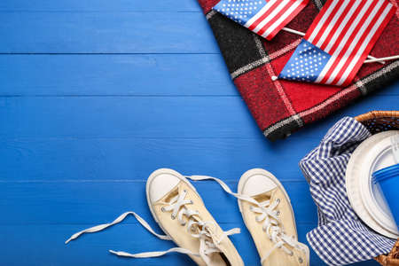 Picnic basket with American flags, plaid and shoes on color wooden backgroundの写真素材
