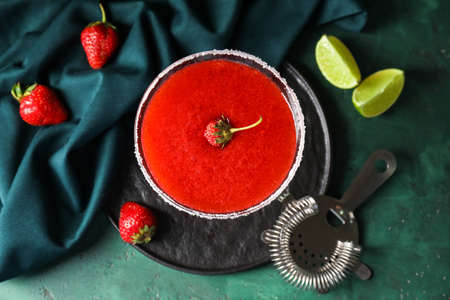 Glass of strawberry daiquiri cocktail and strainer on color backgroundの写真素材