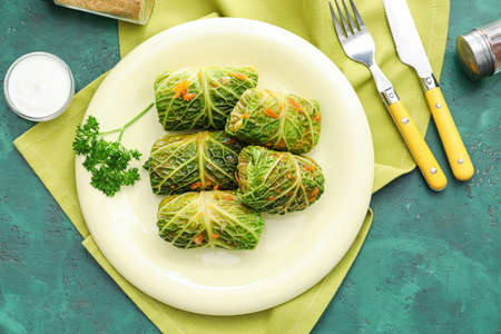Plate with stuffed cabbage leaves and sour cream on color backgroundの写真素材