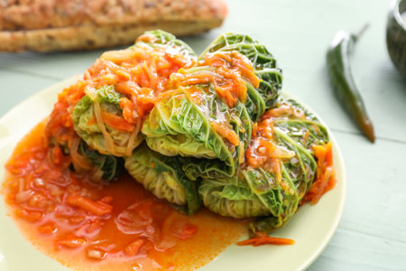 Plate with stuffed cabbage leaves and tomato sauce on color wooden backgroundの写真素材