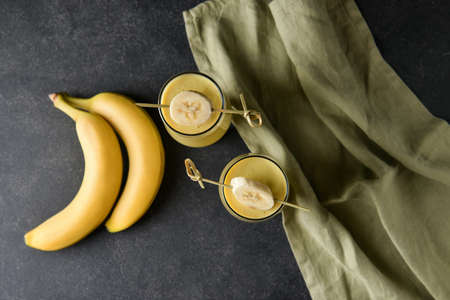 Glasses of tasty banana daiquiri cocktail and fruits on dark backgroundの写真素材