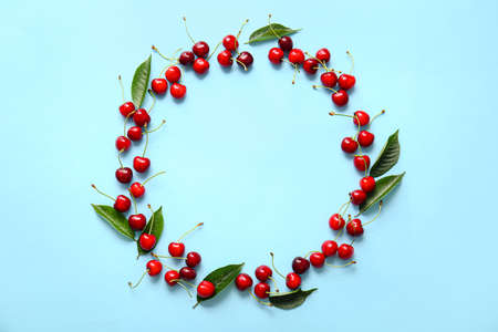 Frame made of tasty ripe cherry on color background