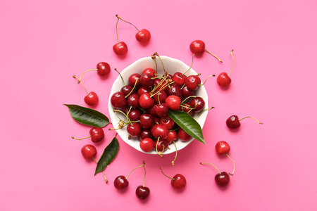 Bowl with tasty ripe cherry on color background