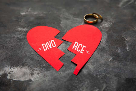 Broken paper heart and wedding rings on grunge background. concept of divorceの写真素材