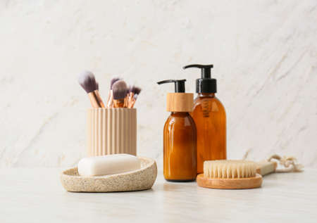 Bowl with soap bar, cosmetics and massage brush on light backgroundの写真素材