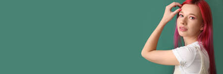 Cool young woman with bright hair on green background with space for textの写真素材