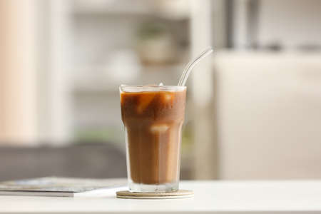 Glass of tasty ice coffee on table