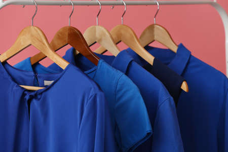 Rack with clean blue clothes on pink background, closeupの写真素材