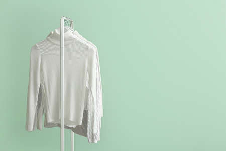 Rack with clean white sweaters on green backgroundの写真素材