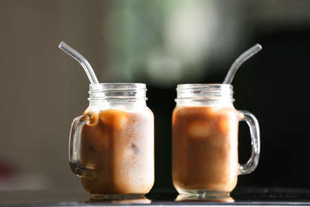 Mason jars of tasty ice coffee on table