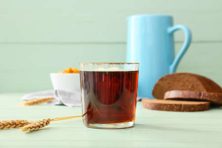 Glass of fresh kvass on color wooden background