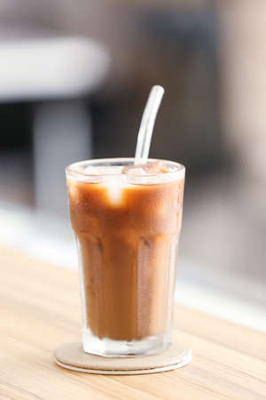 Glass of tasty ice coffee on table