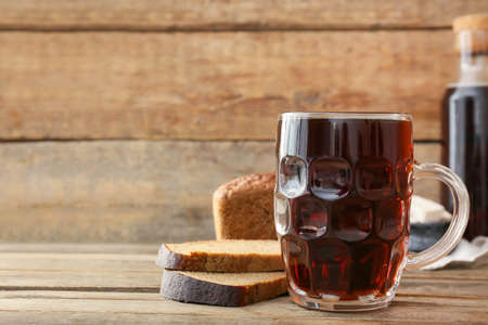 Mug of fresh kvass on wooden background