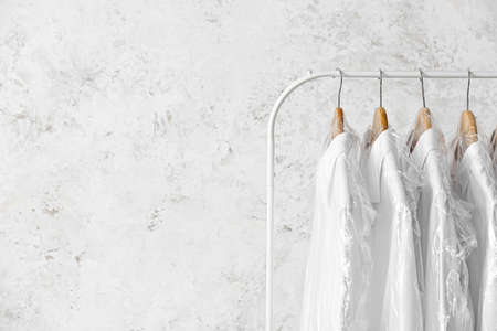 Rack with clean white shirts in plastic bags on grunge backgroundの写真素材