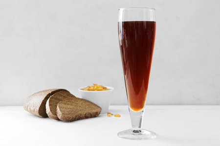 Glass of fresh kvass and bread on light background