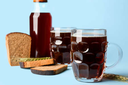Mugs of fresh kvass on color background