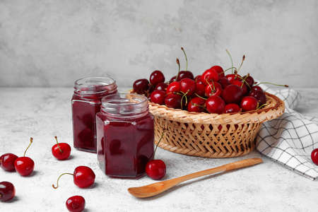 Composition with sweet cherry jam on light background