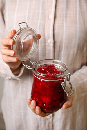 Woman holding glass jar with sweet cherry jam, closeupの写真素材