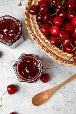 Composition with sweet cherry jam on light background, closeup