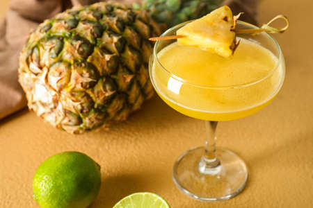 Glass of pineapple daiquiri cocktail on color background