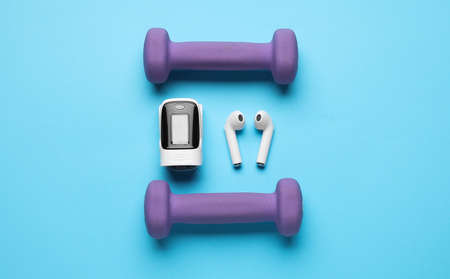 Pulse oximeter, earphones and dumbbells on color backgroundの写真素材
