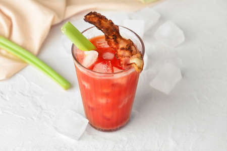 Glass of bloody mary cocktail garnished with bacon and celery on light backgroundの写真素材