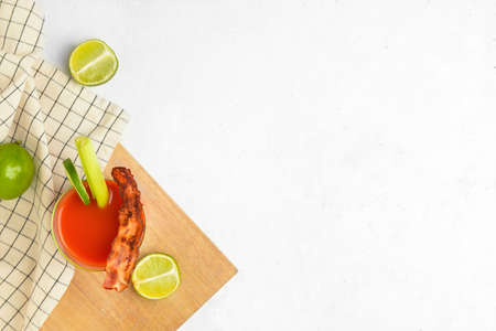 Glass of bloody mary cocktail garnished with bacon and lime on light backgroundの写真素材