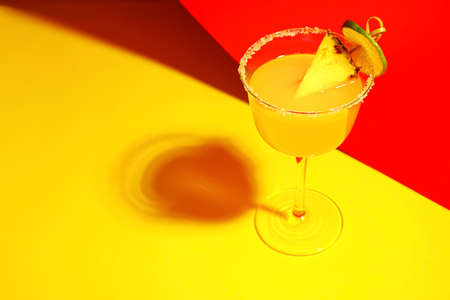 Glass of pineapple daiquiri cocktail on color background