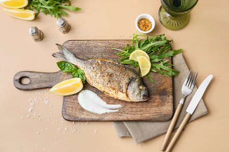 Wooden board with fried dorado on color backgroundの写真素材