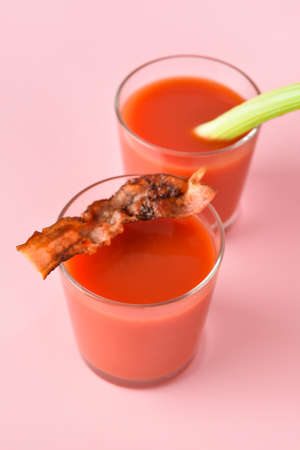 Glasses of bloody mary cocktail garnished with bacon on color backgroundの写真素材