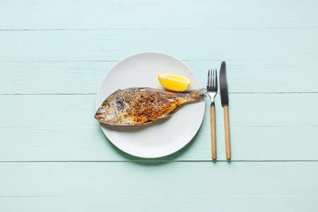 Plate with fried dorado on color wooden backgroundの写真素材