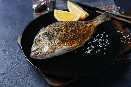 Plate with fried dorado on color background
